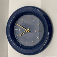 Front view of the vintage 1980's Mikasa quartz wall clock with dark blue frame and gold markers and hands.