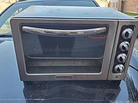 Front view of KitchenAid countertop stove oven showing glass door, handle, and control knobs on the right side.
