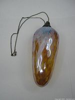 Side view of the handblown glass ornament showing the graduated color pattern and attached chain