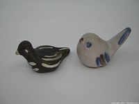 Two handmade pottery bird figurines side by side on white background, showing color and shape details.