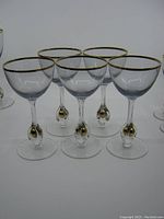 Front view of all five MCM Jozef Stanik gold ball stem glasses with amethyst tinted bowls and gold rims.