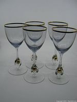 Front angle view of all five glasses showing gold rims and gold balls on stems.