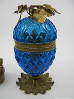 Front and side view of the blue glass lighter with diamond cut pattern, metal base and floral metal lid.