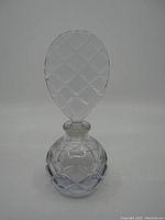 Front view of the vintage purple glass perfume bottle showing the round base and patterned oval stopper.