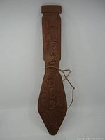 Full view of the hand carved wooden mini paddle with indigenous designs, signed by Willie Jacobson, against a plain white background.