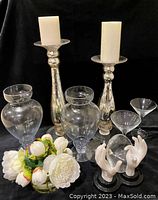Photo showing all items in the lot: two mercury glass candle holders with pillar candles, two clear glass vases, faux white peony flower arrangement in glass vase, three martini glasses, and decorative hand sculptures.