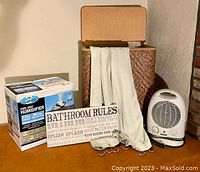Full view of bathroom essentials set: humidifier in box, wicker hamper with lid, heater, shower curtain with grommets, hooks, and bathroom rules sign.
