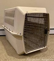 Travel crate with plastic constructed walls and metal wire door, front angled view