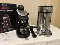 AICook espresso coffee maker with box, scoop, glass carafe next to Hamilton Beach single-serve coffee maker with scoop on table.