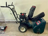 Side profile of snowblower showing auger housing, wheels and discharge chute