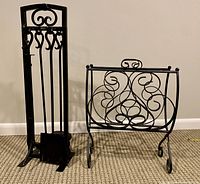 Front view of black wrought iron fireplace tool set and ornate folding log holder side by side on carpeted floor