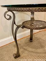Close-up side view showing scrolling iron legs and rope-trimmed circular iron frame with marble shelf support.