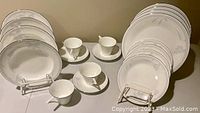 Full set arranged including plates, soup bowls, tea cups, and saucers showing floral design and silver rim details.