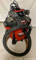 Front angled view of the red and black Craftsman shop vacuum with hose attached and power cord wrapped on top.