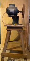 Front view of the sanding/shaping machine with motor and sanding disk mounted on wooden base.