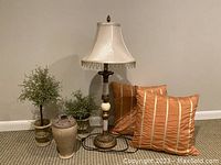 Full shot showing the lamp, ceramic urn, faux topiaries, and pillows grouped together on floor.