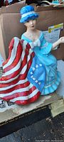 Full view of ceramic figure of Betsy Ross seated with US flag, showing colors and details.