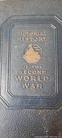 Close-up of the textured dark blue hardcover showing the embossed and gold stamped title 'Pictorial History of the Second World War' with a central design.