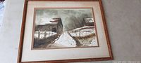 Photo of the framed watercolor painting showing barns and snow-covered pathway, wood frame and double matting visible