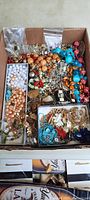 Full lot view showing assortment of colorful beaded necklaces, goldtone chains, and other jewelry pieces in a box.
