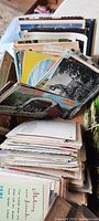 Box with multiple stacks of vintage postcards, varied subjects including black and white images