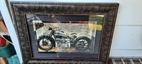 Full view of the framed wall art with visible antique motorcycle image and dark textured frame.