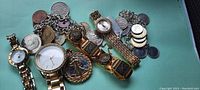 Photo showing watches, coin bracelets, and Standing Liberty coin necklace arranged on flat surface.