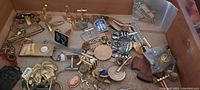 Photo of wooden box interior showing various mixed pins, cuff links, tie tacks, and small service pin scattered inside.