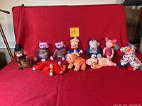 Photo showing the full lot of 10 Beanie Babies arranged on red cloth including Porky Pig, Ohio Bicentennial Bear, and Disney Piglet along with colorful bears and clown.