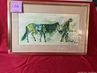 Framed DeGrazia print showing a man leading a horse, signed by the artist. Neutral color tones and impressionistic style.