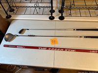 Three golf swing aids laid out on a white table: Speed Stik red shaft, Medicus silver iron-style club, and Tour Striker club. Photos show different angles.