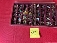 Overhead photo of the full jewelry tray showing multiple compartments with earrings and pins, plastic lid visible and loose.