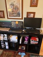 Entire lot displayed on black cubical shelf: HP laptop center-left, LG monitor and Dell keyboard center-right, various peripherals and books below.