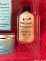 Close-up of Living Grace perfumed olive oil body scrub bottle showing product details and size of 60 ml/2 fl oz.