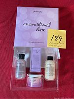 Full view of the Unconditional Love kit with all 4 small sized body care items visible in plastic packaging alongside branded informational card and handwritten lot identifier.
