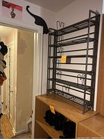 Photo of entire dark gray steel foldable CD rack, showing six fixed shelves and overall structure on a wooden shelf