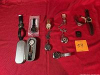 Full assortment of eleven watches displayed on red background. Includes wristwatches with metal and leather bands, and pocket watches with chains. Some watches in tin boxes.