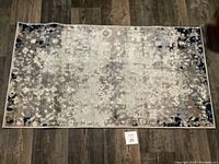 Photo of the rectangular taupe, cream, and navy blue area rug showing full rug on dark wood floor