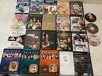 DVD and PlayStation game assortment with cases and discs visible including animated movies, TV series, and music DVDs along with video game discs.