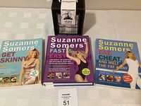 Three Suzanne Somers weight loss books arranged side by side on a table covered with white cloth.