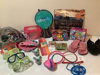 Photo of entire assortment showing skipping ropes, water goggles, flip flops, black water shoes, Skip-It toy, beach paddles in case, shopkins puzzle, and other outdoor toys.
