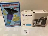 Photo showing boxed One Second Plumber drain clearing tool and Moen Manor 4871 laundry faucet in original packaging with item tag 43