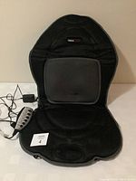 Full view of black Obus Forme seat cushion with wired remote and power adapters laid flat, showcasing the design and included accessories.