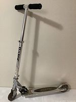 Front and full side view of silver Razor kick scooter showing entire scooter including handle grips, front wheel, and deck