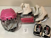 Overview of all items showing two pairs of white figure skates, Bauer helmet, elbow pads and skate guards grouped together.