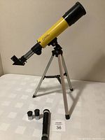 Yellow National Geographic branded telescope mounted on silver tripod with black fittings, angled to left side.
