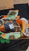 Box of mixed Halloween decorations including vintage hanging bats, spider web decorations, and pumpkin decorations in orange, black, green colors.