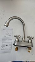 Front view of the Shaco JLT010L faucet showing curved spout, installation hardware, and instruction sheet.