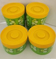 Image showing four green plastic canisters with yellow daisy pattern and yellow lids.