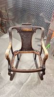 Full view of antique wooden rocking chair frame without seat or upholstery, showing curved arms and rockers.